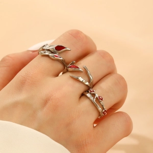 Macro detail of three-piece silver gothic rings with red enamel floral accents