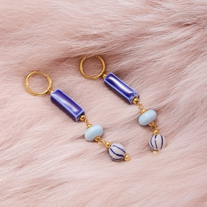 Close-up of vintage blue ceramic tassel earrings on pink faux fur texture background