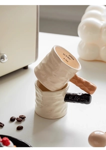 Detail view of stacked ceramic espresso measuring cups with 3oz scales and textured finish