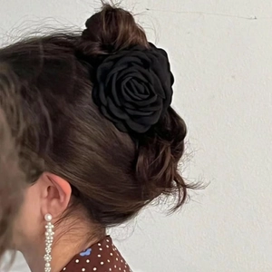 Detail of elegant black fabric rose hair claw clip worn on a French style bun hairstyle