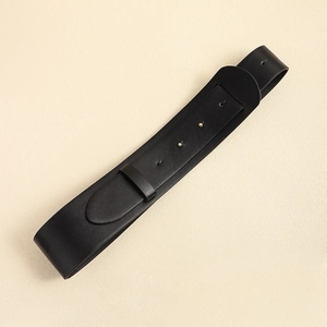 Detail of a wide black leather belt with a metal buckle and loop on a textured surface
