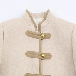 Détail de veste beige avec col montant, texture du tissu et boutons décoratifs dorés