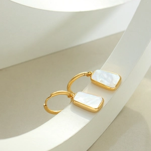 Boucles d'oreilles dorées avec pendentifs rectangulaires en nacre sur support blanc
