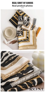 Detailed close-up of leopard print faux silk scarf with chain pattern on white tray