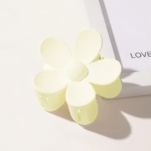 Detailed view of a matte yellow flower-shaped hair claw clip with a five-petal design