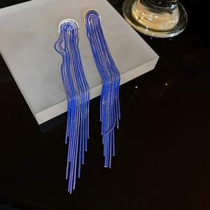 Detail view of long blue chain fringe earrings with golden top piece on display stand