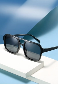 Detail of square black sunglasses on geometric blocks showing UV protective grey lenses
