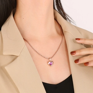 Detail of rose gold rope chain with a heart-shaped pendant featuring a pink stone