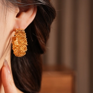 Macro detail of 24k gold plated bird nest textured hoop earrings on model