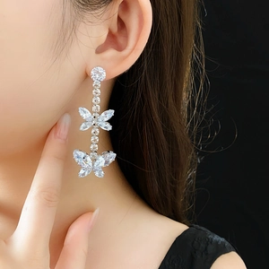 Gros plan de boucles d'oreilles papillon en argent avec zircone portées par un mannequin