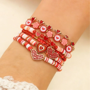 Detalle de pulseras de cuentas de arcilla roja con dijes de corazón dorado y rosas