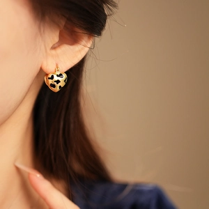 Close-up of heart-shaped leopard print earrings worn by a model in soft lighting