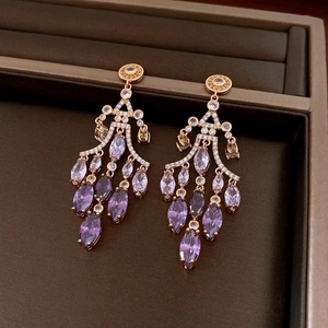 Detail of luxury gold tassel earrings featuring purple marquise crystals and tiny diamonds
