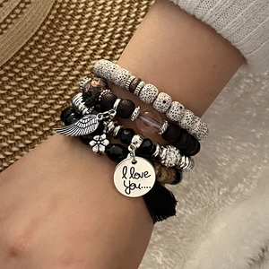Close-up of bohemian beaded bracelet set with silver wing charm and black tassel detail
