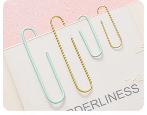 Detail of macaron green and gold metal paper clips on a white grid paper background