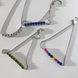 Detail of four adjustable stainless steel bracelets with colorful gemstone charms on white