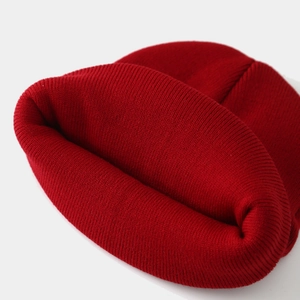 Detailed close-up of dark red ribbed knit beanie showing high-quality fiber texture