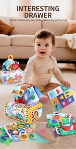 Baby tissue box toy with educational cloth squares and colorful animal patterns on a rug