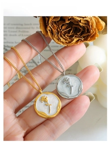 Close-up of vintage rose embossed pendant with pearlescent enamel and gold plating