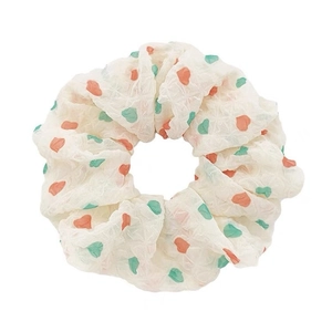 Cream polka dot scrunchie with orange and green spots on a clean white background