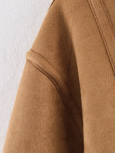 Close-up of camel suede jacket shoulder showing precision double-stitching and fabric texture