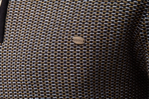 Gros plan du tissu en maille épaisse avec texture jacquard tricolore et détail métallique