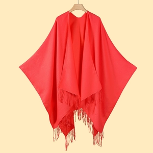 Detailed view of red tassel fringe on classic shawl hanging on a wooden hanger