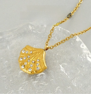 Detailed close-up of shell pendant with white rhinestones on stainless steel gold chain