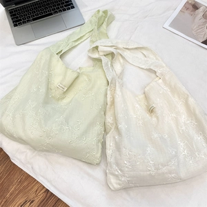 Detail of floral embroidery on canvas tote bags with wide shoulder straps in light green