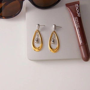 Macro shot of two-tone water drop earrings with polished gold and silver finishes