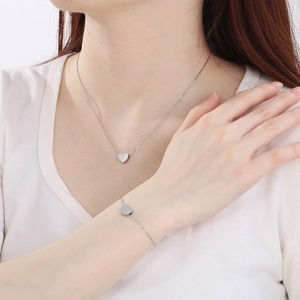 Gros plan sur l'ensemble collier et bracelet cœur argenté porté par un modèle