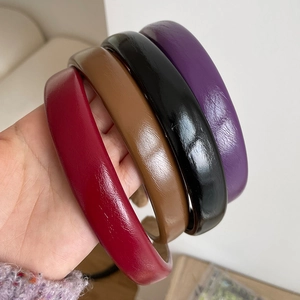 Close-up of four glossy PU leather headbands in red, brown, black, and purple colors