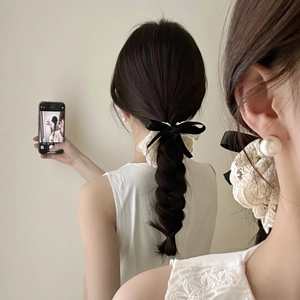 Détail d'un chouchou noeud noir avec dentelle beige et accessoire en perle de haute qualité