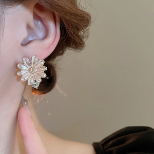 Detailed macro view of daisy stud earrings with pink enamel petals and a sparkling zircon