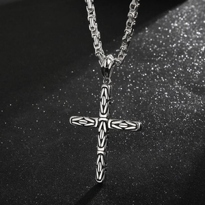 Macro detail of silver stainless steel cross pendant with chunky Byzantine chain link
