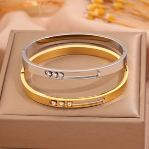 Macro detail of gold and silver steel bangles with sliding triple diamond design