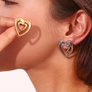 Close-up of double layered hollow heart studs in gold and silver on a model ear