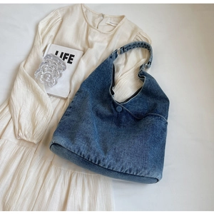 Detail of blue denim hobo bag featuring metal ring connectors and button accent on fabric