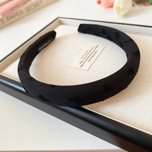 Detail of handmade padded black headband with flocked bow patterns and interior label