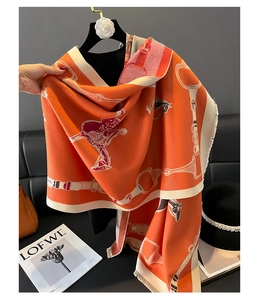 Close-up of thick orange horse pattern shawl scarf with fringe and soft texture detail