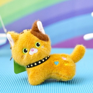 Macro detail of a cute ginger plush cat keychain with a black spiked collar and embroidery