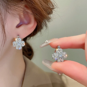 Sparkling silver four-leaf clover stud earrings with cubic zirconia worn on ear