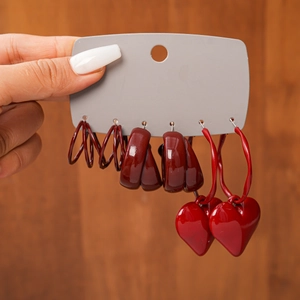 Six-piece set of vintage red geometric hoop earrings on grey display card over wood