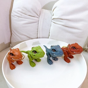 Set of four colorful cartoon dinosaur keychains on a white tray with golden rings