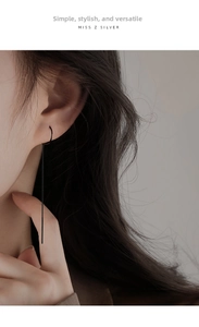 Detail of minimalist black long tassel chain earrings worn on a female model
