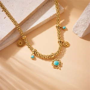 Gold beaded chain necklace with turquoise flower and tree of life pendants on stone
