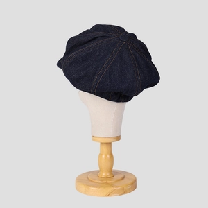 Gros plan d'une casquette gavroche en denim bleu avec surpiqûres orange sur un mannequin