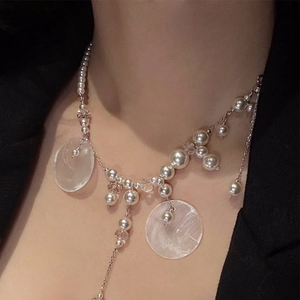 Detail of elegant layered pearl tassel necklace with transparent beads on silver chain