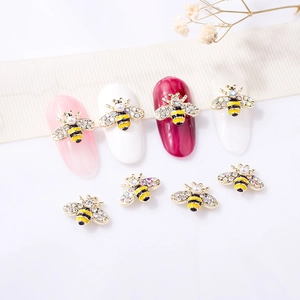 Detailed view of 3D bee nail charms with yellow stripes, pearls, and sparkling crystals