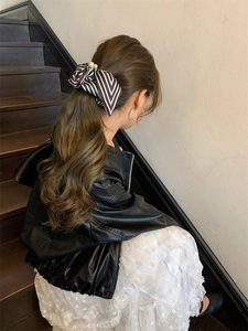 Detail of striped bow hair scrunchie with pearl accent on elegant ponytail hairstyle